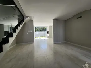 Ambiente interno amplo com piso claro e acesso a uma área externa através de porta de vidro.
