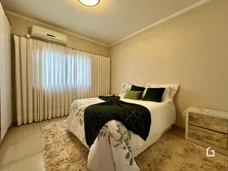 Quarto com cama e cortinas brancas.