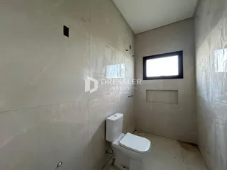 Foto de um corredor interno com um vaso sanitário e uma janela.
