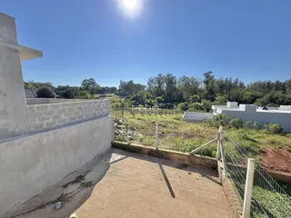 Vista externa de uma propriedade com cerca e vegetação ao fundo.