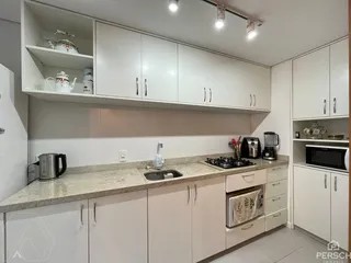 Cozinha moderna com armários brancos e bancadas claras.