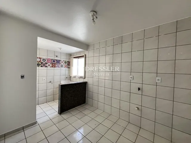 Corredor interno com piso e paredes brancas e azulejadas.