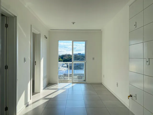 Hall de entrada com piso claro e porta de vidro que dá para a vista externa.
