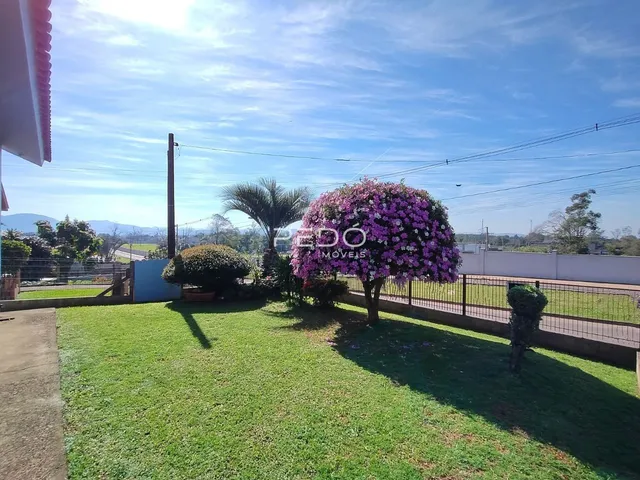 Vista externa de um jardim gramado com vegetação e cerca em Lajeado.