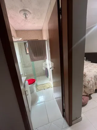 Vista interna de um banheiro com piso de cerâmica e box de vidro.