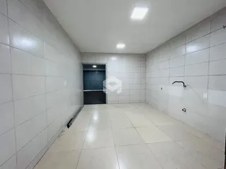 Interior de um corredor com paredes brancas e piso de cerâmica.