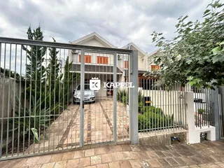 Fachada de uma residência em Lajeado, Brasil, com portão de metal e vegetação ao redor.