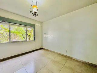 Uma sala interna com grande janela que oferece vista para a vegetação externa.