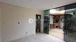 Interior de uma sala com piso de cerâmica e porta de vidro que dá para o exterior.