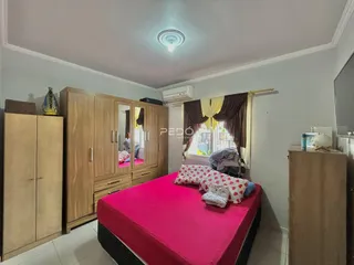 Quarto com armários de madeira e cama rosa em um imóvel no Brasil.
