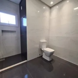 Foto de um banheiro com paredes brancas e piso escuro.
