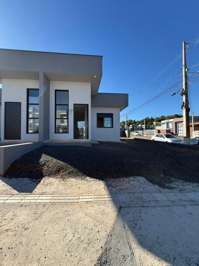 Fachada de uma casa moderna em Lajeado, Brasil, com revestimento branco e detalhes escuros.