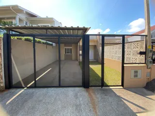 Foto da entrada de um imóvel com portão de metal preto.
