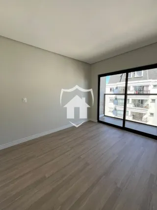 Ambiente interno de uma sala com piso de madeira clara e paredes cinzas.