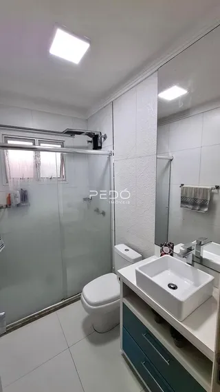 Foto de um banheiro com box de vidro e revestimento branco.