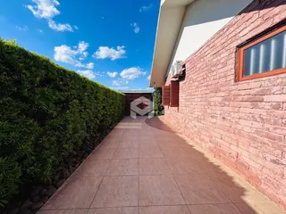 Vista da fachada de uma residência com muro de tijolos e jardim.