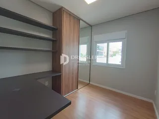 Interior de um cômodo com piso de madeira e estantes de madeira.