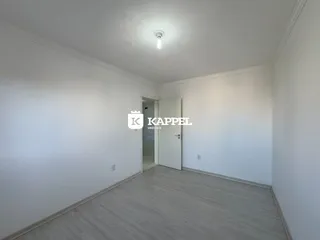 Foto de um cômodo interno com paredes brancas e piso de madeira clara.