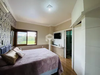 Quarto com cama e janela de madeira no interior da residência.