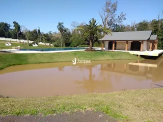 Vista externa de uma propriedade com jardim e corpo d'água.