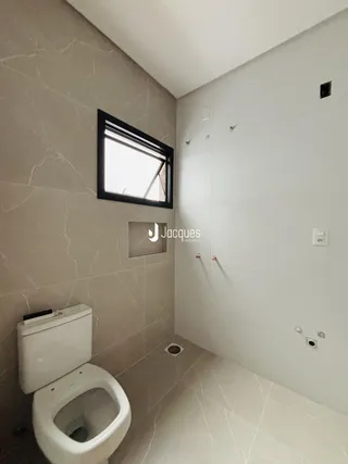 Foto de um banheiro com piso de cerâmica e paredes claras.