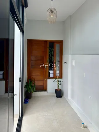 Hall de entrada com portas de madeira e piso de cerâmica clara.