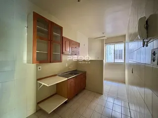 Cozinha com armários de madeira e piso cerâmico em um imóvel.