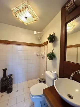 Foto de um banheiro com revestimento de azulejos brancos e detalhes em madeira.