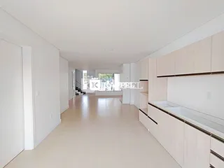 Corredor longo com paredes brancas e armários de cozinha ao lado.