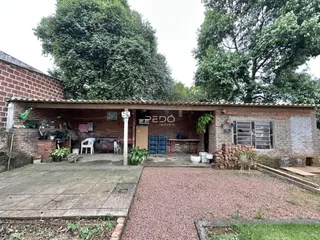 Fachada de uma casa de tijolos com área externa de terra batida.