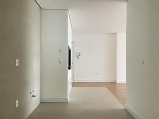 Hall de entrada com paredes brancas e piso claro.