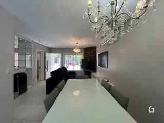 Sala de estar com mesa de vidro e sofá escuro.