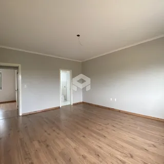 Uma sala com piso de madeira clara e paredes brancas.