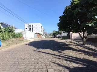 Vista externa de uma propriedade com calçamento e vegetação no primeiro plano.