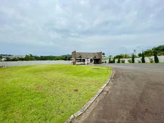 Vista externa de uma propriedade com gramado verde e cerca.
