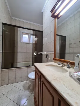 O interior de um banheiro com revestimento de cerâmica e bancada de mármore.