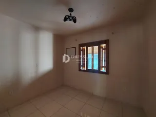 Sala de uma residência com piso de cerâmica e uma janela de madeira.