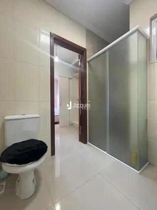 Interior de um banheiro com piso de cerâmica e box de vidro.