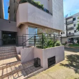 Vista externa de um prédio residencial em Lajeado, Brasil, com muro e vegetação.