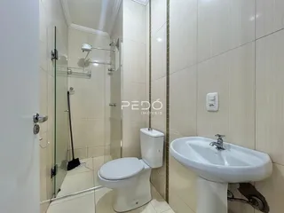 Banheiro moderno com box de vidro e louças brancas.