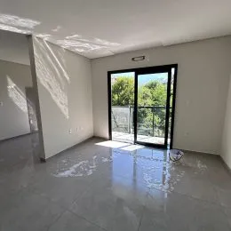 Ambiente interno com piso claro e porta de vidro que dá para o exterior.