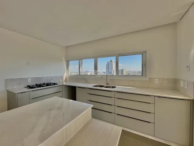Vista da cozinha com armários e bancadas em mármore.