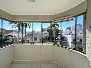 Vista de uma área interna com grandes janelas de vidro mostrando o entorno da propriedade.