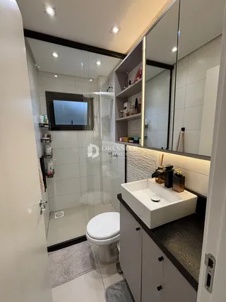 Foto de um banheiro com box de vidro e bancada moderna.