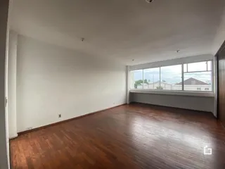 Ambiente interno com piso de madeira e grande janela.