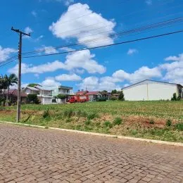 Vista externa de uma propriedade com gramado e paisagem sob um céu azul.