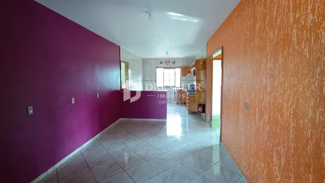 Corredor interno de uma residência com paredes coloridas e piso de cerâmica.