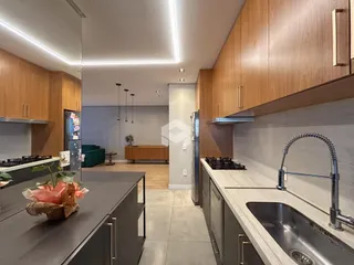 Vista da cozinha moderna com armários de madeira e bancadas claras.