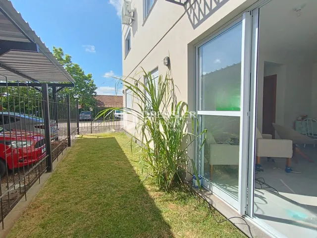 Vista da fachada de uma residência com jardim gramado e porta de vidro.