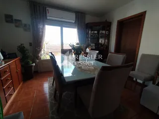Sala de estar com piso de madeira e grandes janelas.